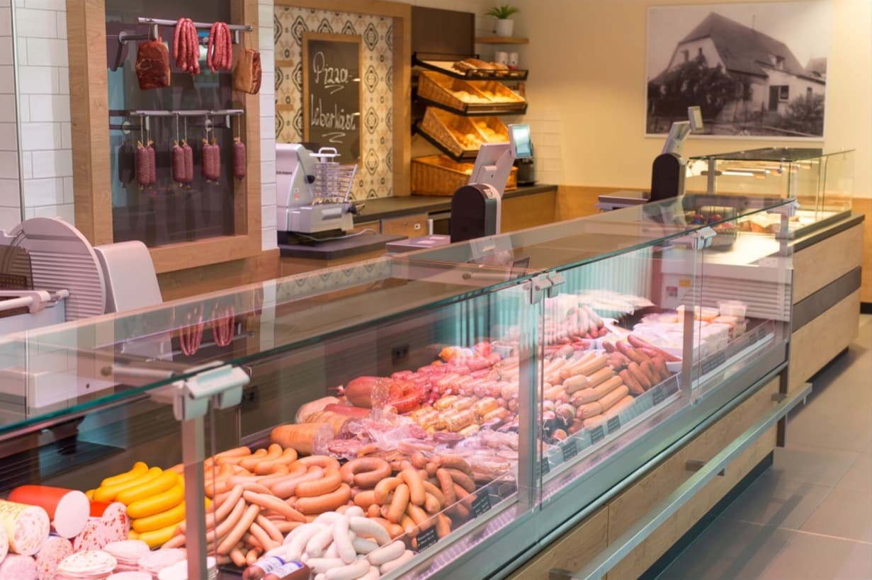 Theke mit Wurstwaren in der Metzgerei Schels, an der Wand ein altes Foto des Hauses